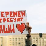 person holding red and white love is love print board